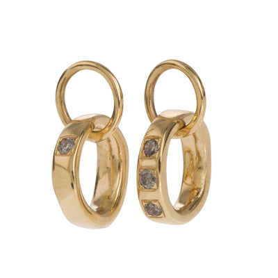 Classic, Twisted Hoop Earrings in Gold. The Classic Twist circles can be purchased plain or with diamonds. All diamonds are set in pave style framed in a squared line: three diamonds sit together on one side and one diamond on the opposite side. All diamonds are natural in colour and available in black, grey or brown, depending on the metal. The earrings come in White Gold, Yellow Gold, 18K and 9K Gold.